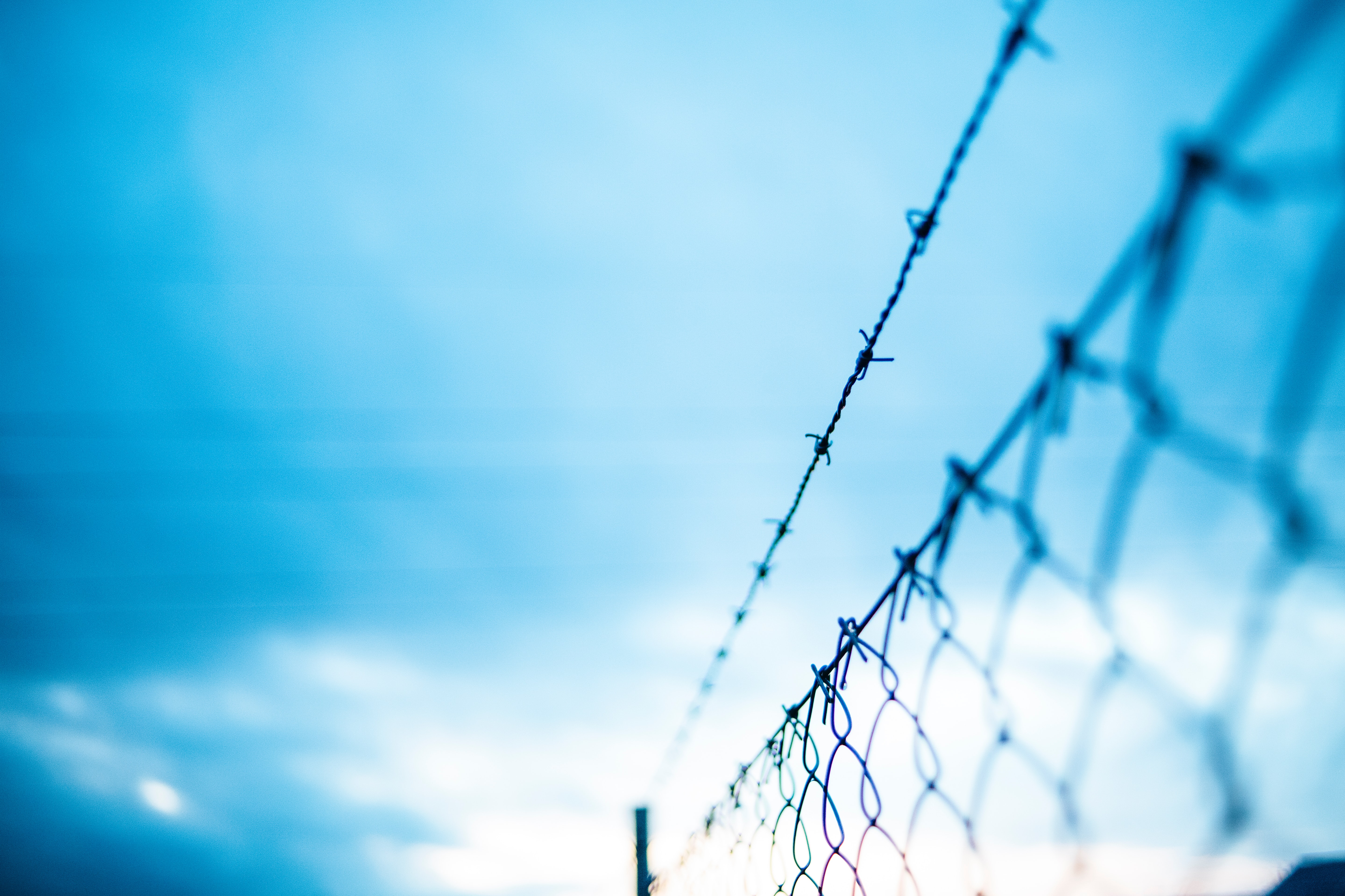 Fence and barbed wire with a blue sky in the background